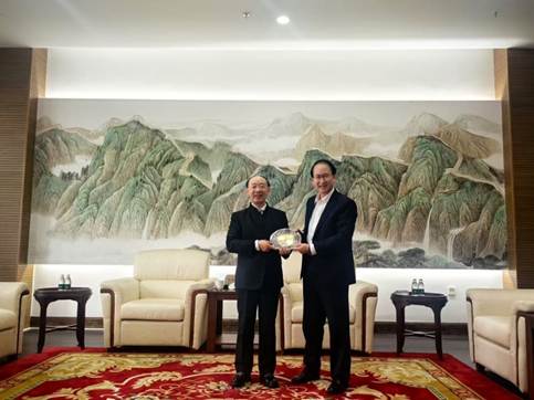 Two men holding a silver object in a room with a painting on the wallAI-generated content may be incorrect.